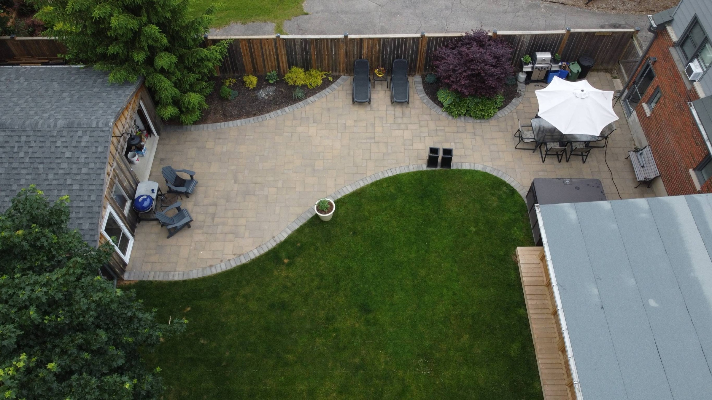 Aerial view of a backyard patio with curved garden beds