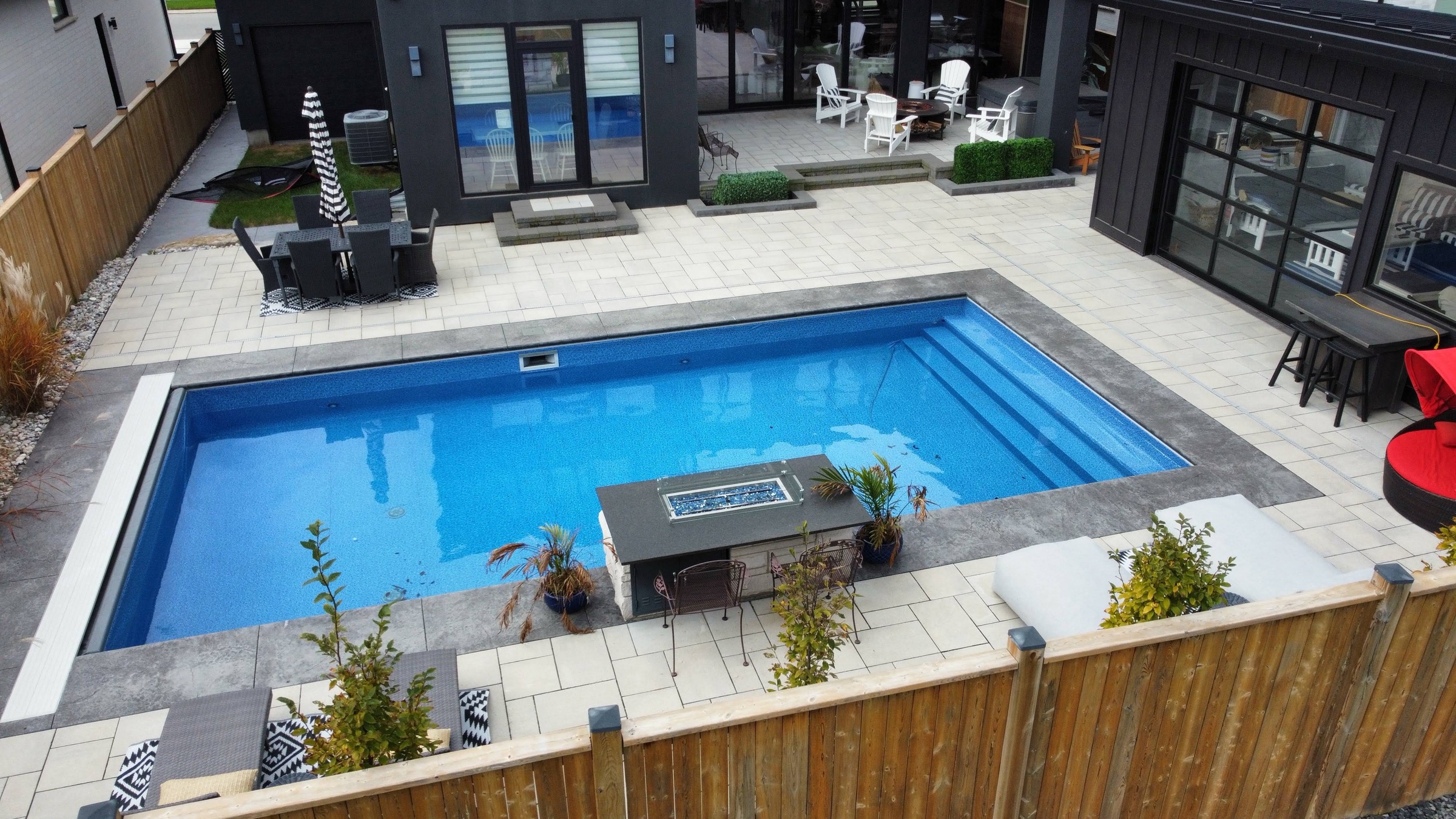 Aerial view of a pool surround and patio behind a modern house